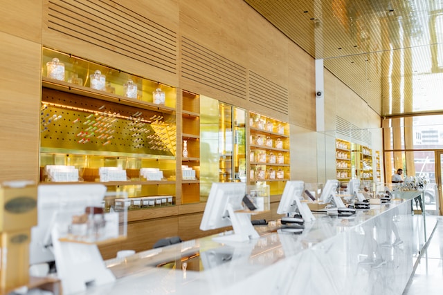 Interior of a cannabis dispensary with natural wood display cases behind a glass counter top and dispensary POS.
